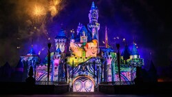 Sleeping Beauty Castle illuminated with a projection of Peter Pan while fireworks burst above during the Wondrous Journeys nighttime show