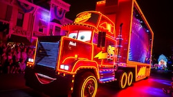 Mack illuminated near Main Street, USA at the Paint the Night Parade