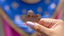 Una mano sosteniendo 3 monedas aplastadas de la Celebración del 70.º Aniversario de Disneyland con Minnie Mouse, Mickey Mouse y Pluto