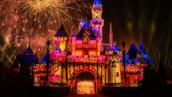 Sleeping Beauty Castle illuminated at night with lighting and fireworks