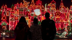 A silhouette of a family looking at lights during Holiday Time at the Disneyland Resort Guided Tour