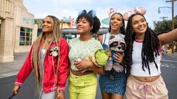 Four young women smiling as they walk through Cars Land