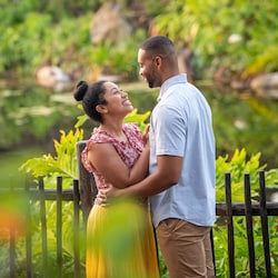 A couple embrace and look into each other’s eyes, surrounded by lush foliage