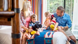 2 parents and their 2 kids share a laugh in their hotel room