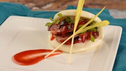 A bao bun filled with sliced pork and micro greens