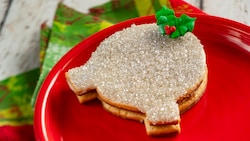 A cookie shaped like the Spaceship Earth attraction, topped with icing in the shape of a holly leaf