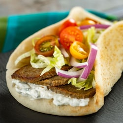 A gyro featuring sliced lamb, lettuce, tomatoes, onions and tzatziki 
