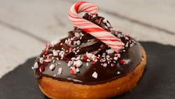 A donut topped with chocolate frosting and a peppermint candy cane
