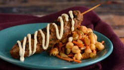 A grilled kebab served with carrot-chickpea salad