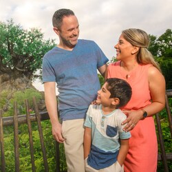 A mom, dad and young boy pose in front of the Tree of Life at Disney’s Animal Kingdom