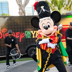 Mickey Mouse, dressed as a drum major, performs with a drumline in front of a Disney on the Yard bus at Disneyland Resort