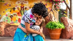 Mirabel Madrigal from Encanto hugging a girl in a Mirabel costume