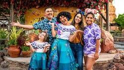 A family stands around the character Mirabel, posing for a picture.