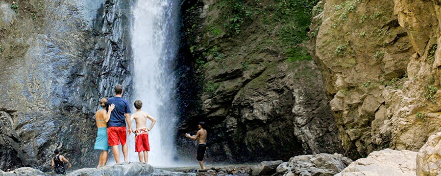 People stand in front of a tall waterfall pouring down a rock face
