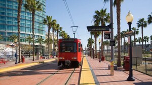 A cable car between rows of palm trees in a city
