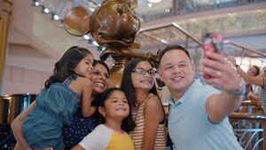 A young family of 5 snapping a selfie together in the lobby of a Disney cruise ship