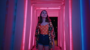 A teenage girl walking through a corridor of neon lights