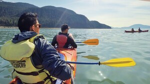 2 men with lifejackets paddling a 2 seat kayak through a body of water
