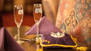 2 taças de champanhe ao lado de uma tiara em uma almofada de cetim
