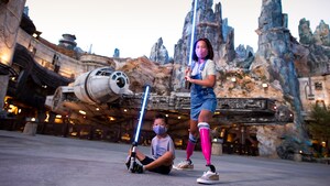 Adult and child posing with lightsabers in Galaxy's Edge