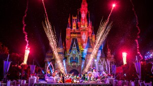 A festive Cinderella Castle illuminated at night with lasers and fireworks as over a dozen Disney Characters wave from in front, dressed for the holiday season, along with Mickey and Minnie in a sleigh