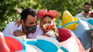 Daughter and Father enjoy riding Dumbo the flying elephant with face coverings
