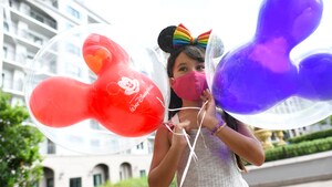 Young girl stands in front of Disney's Rivera Resort with two Mickey balloons