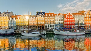 Buildings of similar heights sit side by side before a canal populated by sail boats