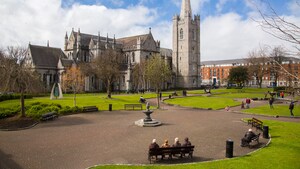 Cuatro mujeres ancianas sentadas en una banca del parque, frente a un gran castillo antiguo en Dublín, Irlanda