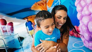 A young mother in a water arcade hugs her small son as they enjoy a laugh together