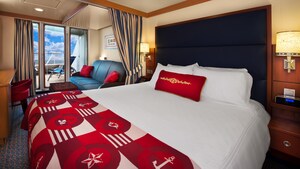 A stateroom with a desk, verandah, coffee table, sofa, privacy curtain, bed, 2 end tables and 2 sconces
