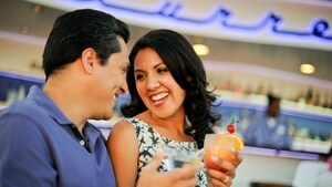 A smiling couple chats with cocktails in hand