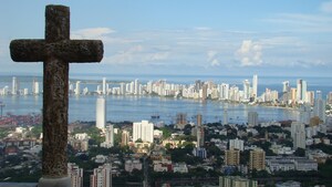 A Christian cross overlooks a sprawling city by a bay