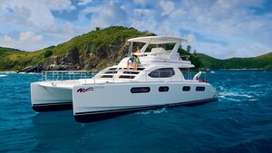 A couple sits on a ledge just below the cockpit of a motor catamaran