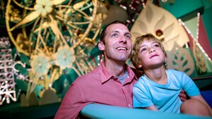 A father and his son watch in wonder while riding aboard “it’s a small world” at Magic Kingdom park