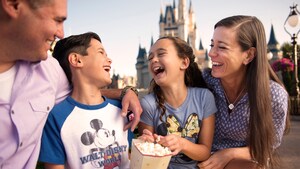A father, mother, son and daughter laughing while eating popcorn near Cinderella Castle