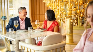 Una pareja sentada en una mesa en el restaurante exclusivo para adultos Enchanté en Disney Wish