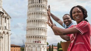 A couple pretends to lean against the Leaning Tower of Pisa in Italy