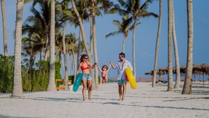 2 parents holding hands with their toddler and swinging her between them on a beach in the Mexican Riviera