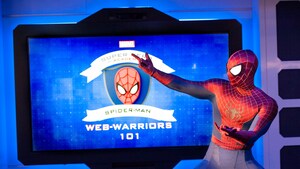 Spider Man posing with a screen that reads ‘Web Warriors 101’