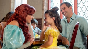 Ariel smiles with a little girl who is dressed like Belle