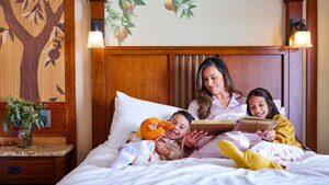 A mother reading to her 2 children in bed at Disney's Grand Californian Hotel & Spa