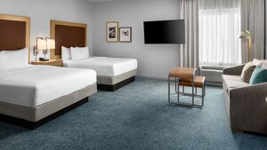 A hotel resort suite bedroom with a sofa, coffee table, TV, nightstand and 2 beds