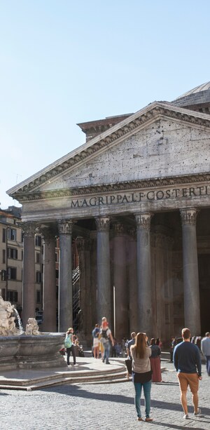 Guests exploring a plaza containing a Greek temple with columns and a triangular cornice