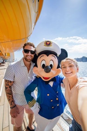 A young couple posing with Captain Mickey Mouse on a Disney cruise ship