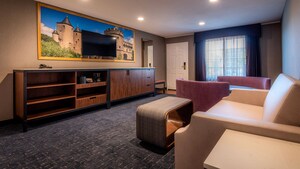 Flat screen TV mounted on a mural of a castle above a long dresser across from a sofa, coffee table and table and chairs
