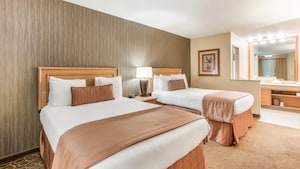 Two double beds with wooden headboards separated by a nightstand with a lamp