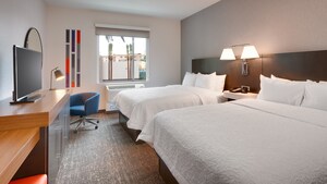 A hotel room with 2 queen size beds, a television and modern design