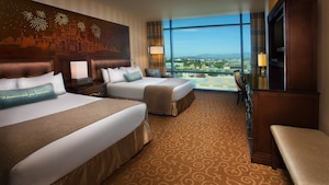 Two queen beds with magical headboards across from a bench, TV-dresser and desk