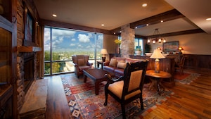 A rustic living room with a floor-to-ceiling window and, beyond, a dining area
